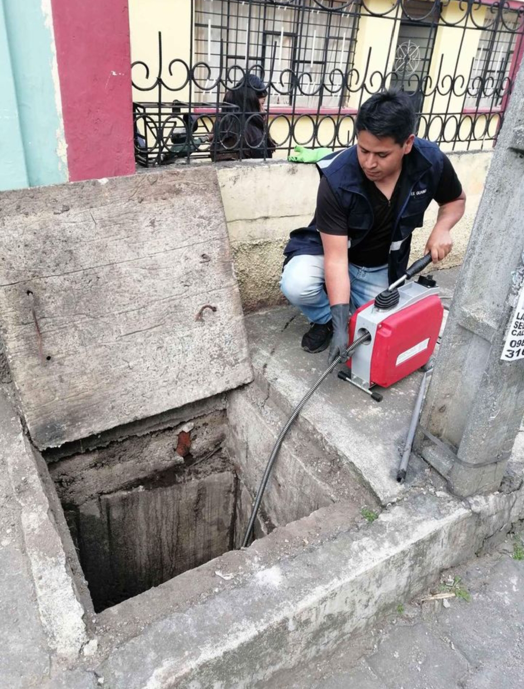 Técnico realizando limpieza en caja de inspección
